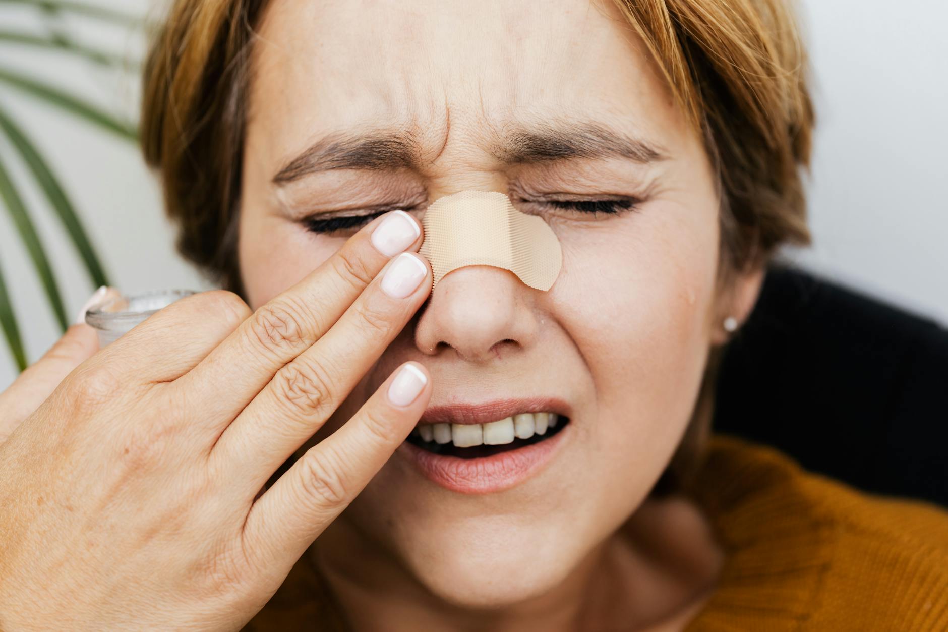hurt woman touching the bandage on her nose